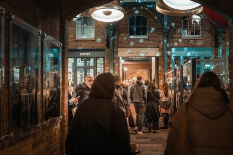 Evening view of a busy passage with people and shimmering lights above the shops, AppleMarket,