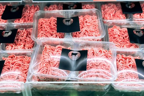 Neatly packed minced meat trays are displayed on a refrigerated supermarket shelf. Each tray is