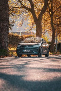 Car on autumn road flanked by sun and trees, electric car VW ID5, Deer Carsharing, Gechingen, Black