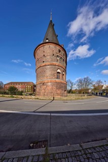 Lübeck Holstentor, side view, blue sky with fair weather clouds, street Holstentorplatz, Hanseatic
