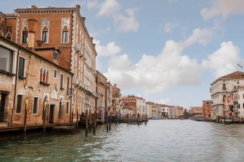 View of Venice's picturesque canal lined with historic buildings under a partly cloudy sky. The