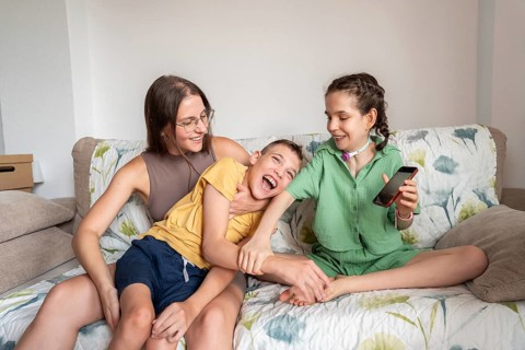 A loving family spends quality time on the couch. The girl with a tracheostomy and her brother with