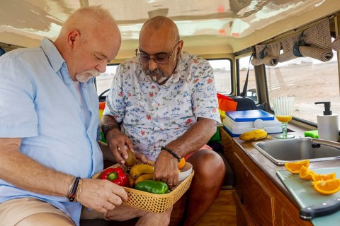 Gay senior couple enjoys preparing a fresh, colorful meal inside their off-road vehicle during a