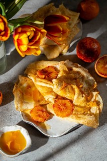 A delightful presentation of Crepes Suzette, featuring thin pancakes draped in a rich, caramelized