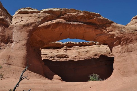 A natural sandstone arch rises under a clear sky in a desert landscape, Arches National Park, Utah,