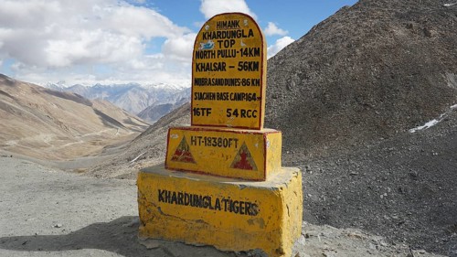 Signpost on dusty Khardung-la Pass in the mountains with sweeping views of surrounding mountains
