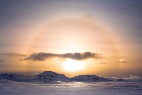 A stunning winter sunrise casts a golden halo over the snowy Icelandic terrain, capturing the