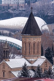 A scenic view of Tbilisi's historic center with snow-covered rooftops. The blend of ancient