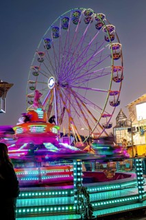 Illuminated Ferris wheel and spinning carousel at night at a fair, carousel and hustle and bustle