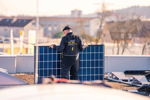Man sets up solar module, prepares installation on the roof, PV installation at OBI Baumarkt,