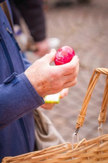 Hand holding a red egg over a basket on a paved road, Easter campaign, Sindelfingen, Böblingen