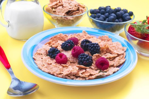 A vibrant breakfast scene featuring a bowl of cereal topped with fresh raspberries and blackberries