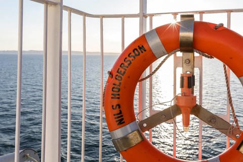 Lifebuoy on the railing of the TT-Line ferry Nils Holgersson with sun on the Baltic Sea