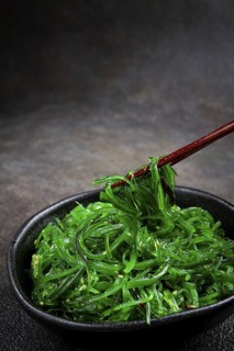 Chuka salad, made from fresh seaweed, with sesame dressing, served in a black bowl, with chopsticks