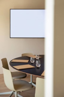 A modern boardroom featuring a circular table, sleek chairs, and a blank screen. Prepared meeting