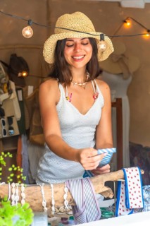 Young woman selling souvenirs at her shop in siargao island, philippines, holding a blue and white