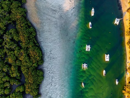 Aerial shot showcasing a tranquil coastal scene with boats anchored by vibrant green water and