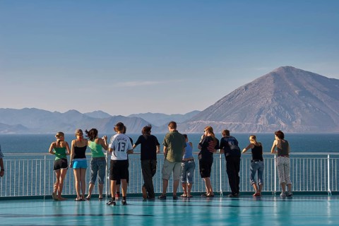 People standing on the deck of a ferry with a view of sea and mountains, Old ferry port in the