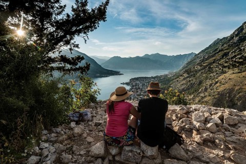 Couple seats on stones over Bay of Kotor, Montenegro.