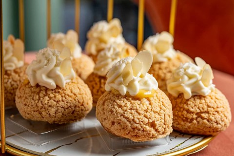 A close up of artisanal cream filled pastries, delicately topped with whipped cream and almond
