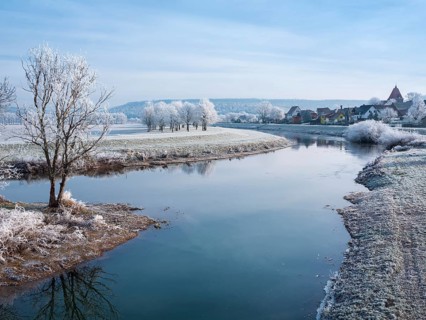 The river Unstrut in the Unstrut valley in winter, fields, trees and forests covered with