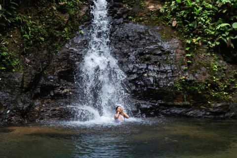 Woman enjoying a scenic waterfall in Choco Andino rainforest, Ecuador. The image captures a young