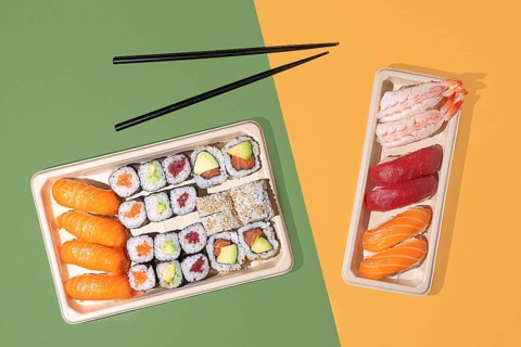 Minimalist overhead shot of sushi takeout boxes on a split color background, featuring nigiri and