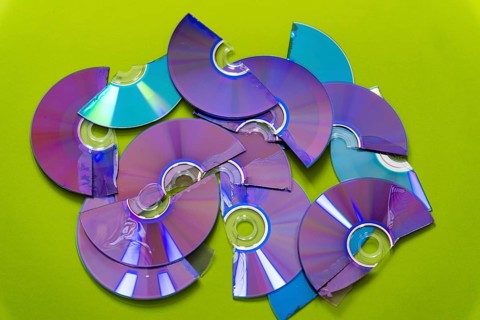 Top view of cut CDs and DVDs against a green background
