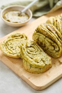 Baked homemade savoury babka plaited bread loaf flavoured with pesto on wooden bread board