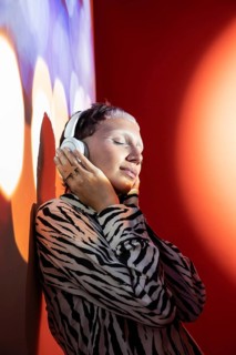 A young, fashionable woman wearing zebra-pattern attire enjoys music on her headphones. Her eyes