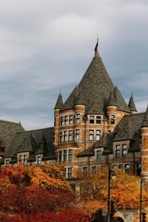 A castle-like building with towering spires sits amidst vibrant fall foliage in Montreal. The