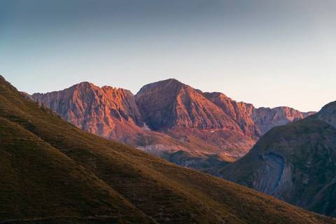 A stunning mountain range basking in the warm glow of the setting sun in summer. The play of light