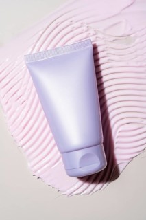Elegant cream-colored cosmetic tube set against a soft, textured background. Showcases a luxurious