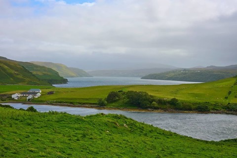 Idyllic green landscape with river, lake and a farmhouse under cloudy sky, Isle of Skye, Scotland,