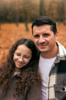 A warm image of a father and daughter enjoying a bonding moment in an autumn setting. The ground is