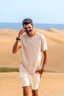 Young male tourist lowering sunglasses while walking on the maspalomas dunes in gran canaria,