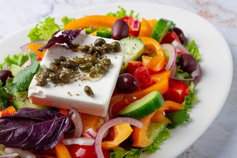 This dish features a salad made with a mix of lettuce, peppers, cucumbers, red onion, and olives.