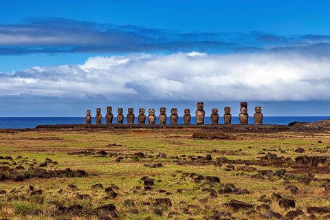 A group of Moai statues under a cloudy sky on a vast grassland, The Moai Statues on Easter Island