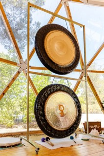 A serene sound therapy setup features two large gongs in a tranquil retreat. Various mallets and