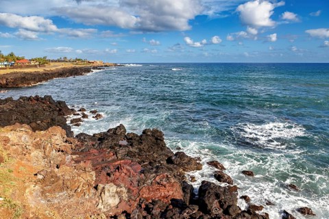Rocky coast with waves crashing against the banks, under a blue sky, the landscape of Easter Island