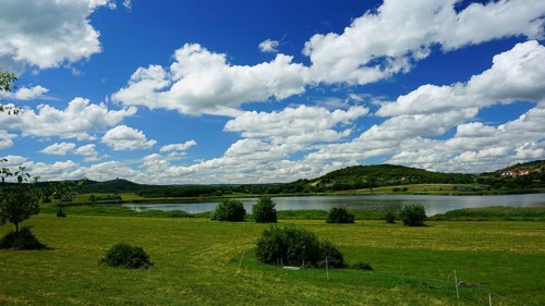 Green landscape with a lake and hills under a blue sky full of white clouds, Velence, Hungary
