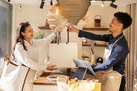 A joyful customer and helpful store assistant exchange a large shopping bag in a stylish bag store,