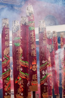 A vibrant display of large red incense sticks adorned with dragons and Chinese characters, emitting