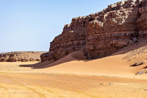 A dry desert landscape with rocks and sand under a clear blue sky, The rock and sand landscape in