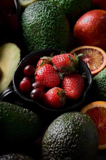 A vibrant assortment of fresh strawberries, avocados, citrus slices, and grapes arranged in an