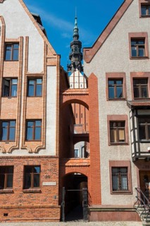 A narrow passageway between two historic brick buildings with a tower in the background, St