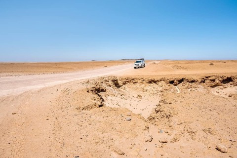 Offroad Car drives trough Rocky landscape, Moon Valley, Namib-Naukluft Park, Namib Desert, Namibia