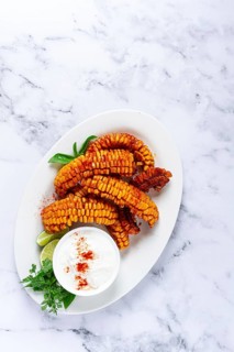 Corn ribs, with cream sauce, spices and lime, appetizer, on a white plate, homemade, no people