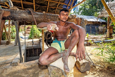The man sits casually in an open wooden structure with a natural background, the sapphire and
