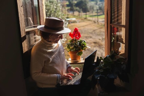 In a cozy countryside home near Barcelona, a senior woman explores the digital world on her laptop